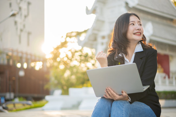 亚洲女商人用笔记本电脑在外面工作，看着商业区的屏幕，职业女性坐在户外图片下载
