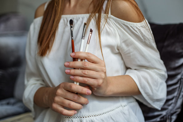 一个女人手里拿着几个化妆刷，她是一个专业的化妆师图片下载