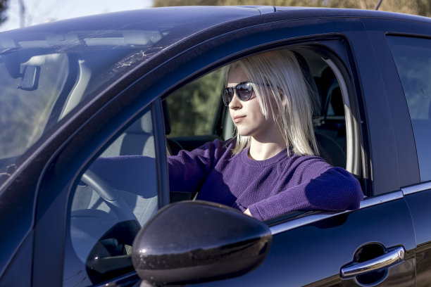 照片肖像的女人戴着太阳镜保持方向盘在汽车图片下载