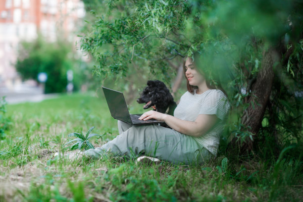 加上大小女孩与长棕色头发与狗和笔记本电脑在公园在自然，年轻的女人和宠物黑色狮子狗图片下载