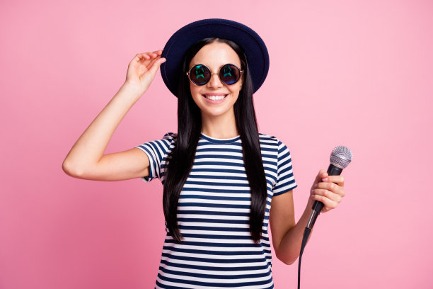 照片肖像微笑的女人拿着帽子麦克风在手中孤立的粉彩背景图片下载