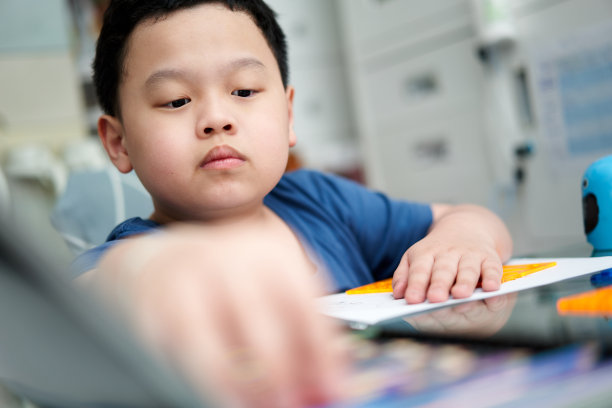 亚洲男孩一边画画，一边在桌上挑选彩色铅笔图片下载