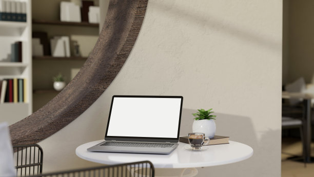 咖啡店内的座位区，白色的桌子上有便携式笔记本电脑和装饰植物。图片下载