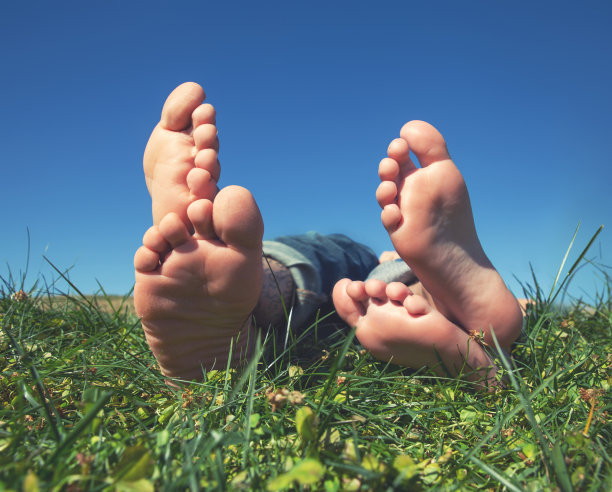 两个人的脚和他们的脚趾躺在草地上的特写，用复古复古的instagram滤镜图片下载