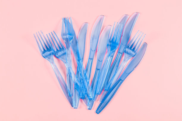 一套塑料透明的刀叉放在粉红色背景的中心图片下载