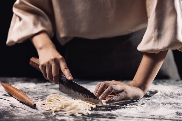将面片切成面条，制作中国传统美食手擀面条的过程——高汤照片图片下载