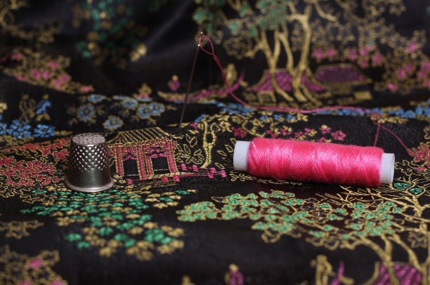 粉红色的线和顶针在古董中国黑色丝绸图片下载