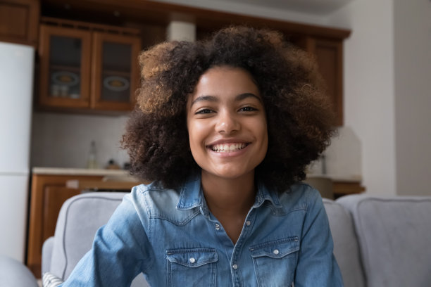开朗的年轻黑人女性坐在沙发上看着摄像头图片下载