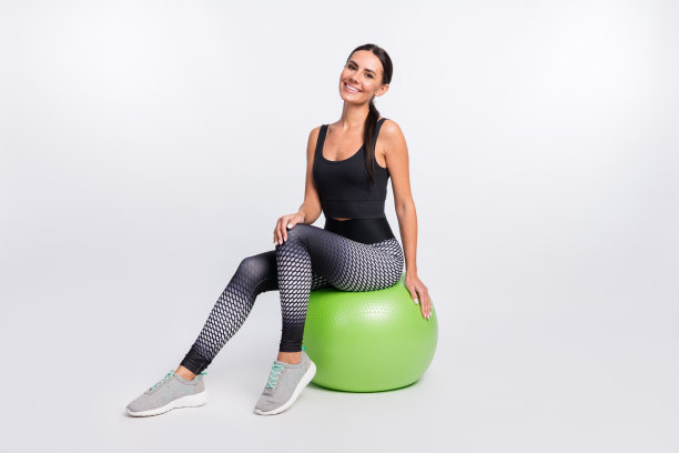 完整的照片快乐的年轻女子坐fit球好心情普拉提孤立的灰色背景图片下载