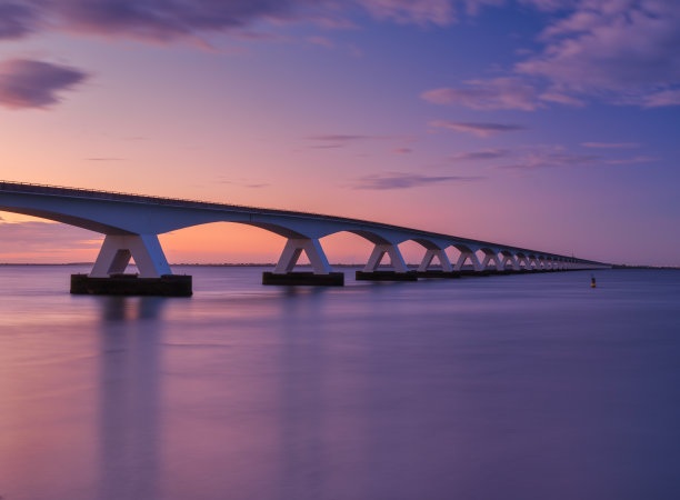 日落时海上的一座长桥。长时间曝光的照片。明亮的日落期间的风景。大海和桥。Zeeland桥,荷兰。图片下载