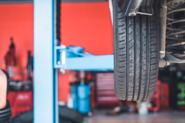 汽车修理工修理轮胎，把车开到男修车厂。解决更换工具和设备的缺陷部件的问题。图片下载