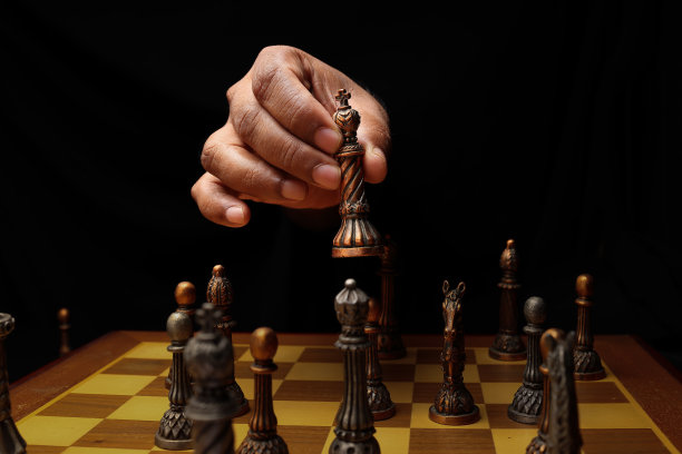 亚洲男性深色皮肤的单手拳头手指在黑色的背景上握着象棋棋子王兵卒在玩着将死棋图片下载