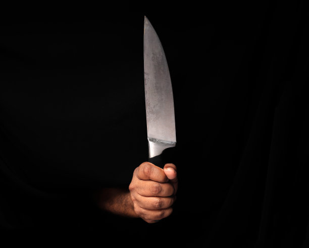 亚洲男性深色皮肤单手拳头手指在黑色背景握不锈钢刀图片下载