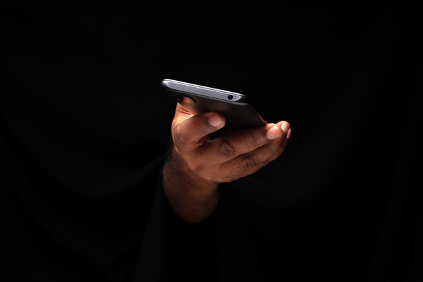 亚洲男性深色皮肤单手握拳手指在黑色背景握用智能手机图片下载