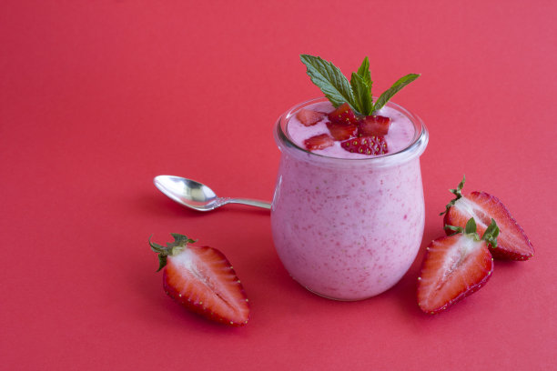 天然牛奶酸奶与草莓在玻璃罐中在红色的背景。特写镜头。副本的空间。图片下载