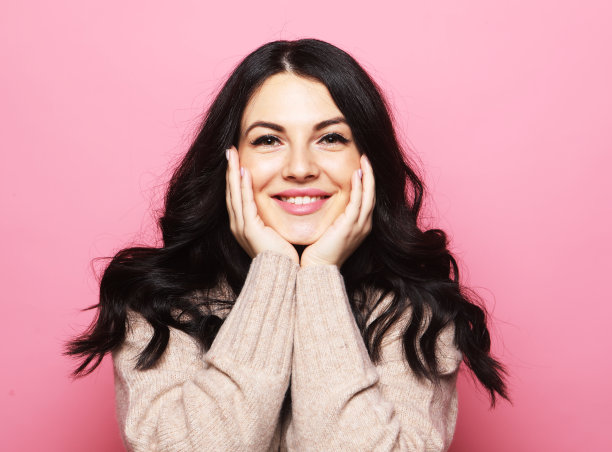 年轻美丽的年轻女子微笑广泛的粉红色的背景图片下载
