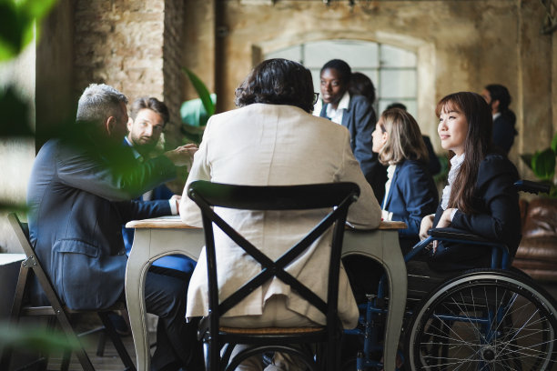 在办公室工作的多种族商务人士 - 聚焦坐在轮椅上的亚洲女士图片下载
