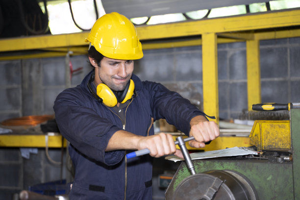 蓝领工人在工厂操作机器图片下载