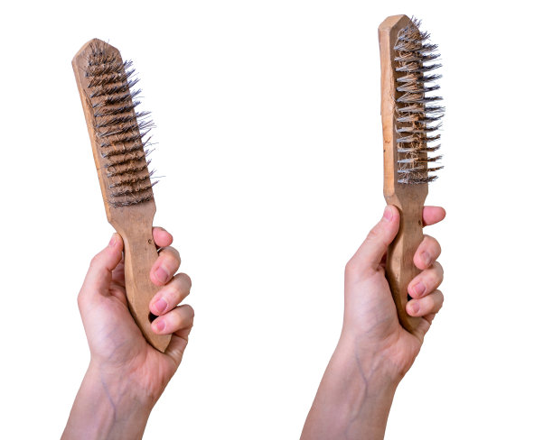 一个男人的手用金属丝刷隔离。握着钢丝刷的手。图片下载