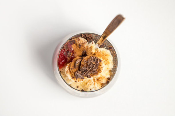 从鼠尾草植物中提取的奇亚籽，非常健康，可以用于许多食谱中。杯子里装着水合的种子和天然酸奶，香蕉，草莓酱，肉桂粉和巧克力屑。图片从上面看到的白色背景。复制的年代图片下载