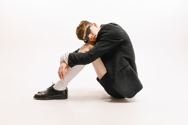 一个年轻时髦的男子，穿着黑色短裤和夹克的学生在白色背景上孤立地摆姿势。时尚、青春、情感、学习、广告的概念图片下载