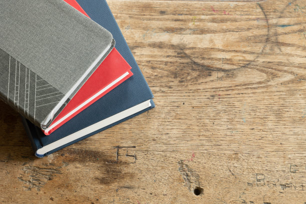 木桌上放着一堆灰色、红色和海军蓝的书图片下载