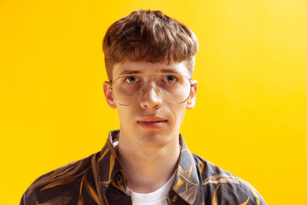 特写肖像英俊的年轻人，青少年看着相机孤立在明亮的黄色工作室背景。人类的情感，面部表情图片下载