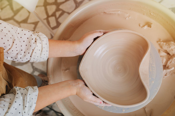 孩子的手把一个软陶碗塑造成心形。图片下载