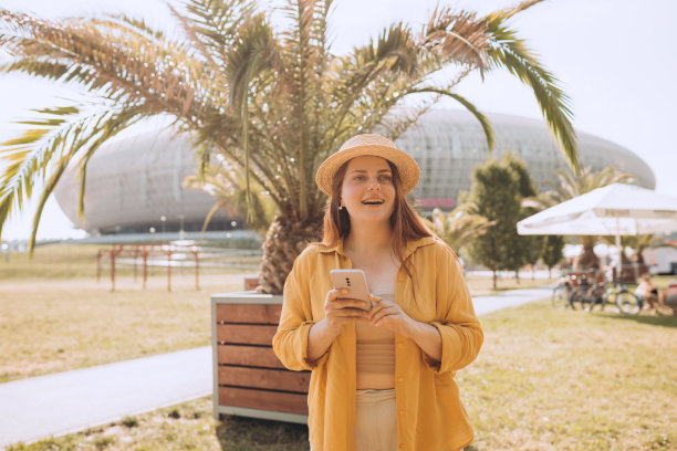 漂亮的笑女孩和智能手机有一个好时光在夏天的周末。棕色头发的时髦女士戴着草帽在户外打电话。电话沟通。城市生活方式的概念。旅行者图片下载