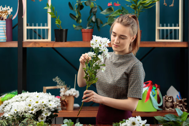花匠制作了一束花。一个年轻的成年女孩选择白色菊花作为花束。图片下载