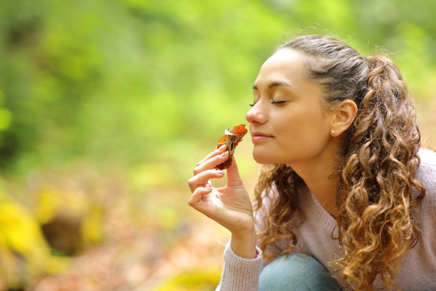 一个女人在森林里闻着枯叶图片下载