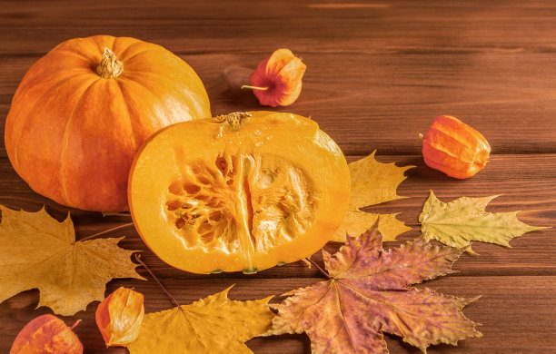 成熟多汁的南瓜在秋叶中，黑色的木质背景。副本的空间。图片下载