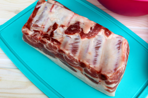 一块带着骨头的鲜肉放在塑料砧板上。图片下载