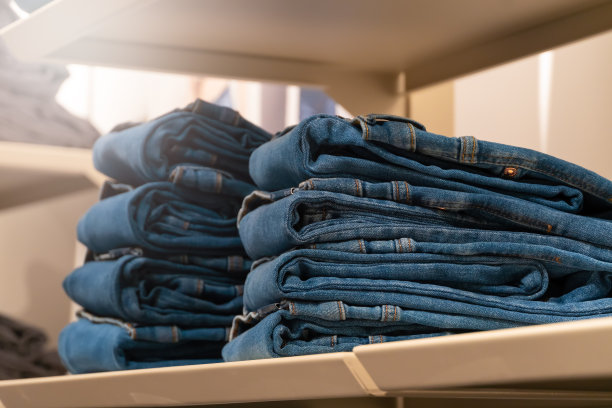 商场里的货架上一堆堆的牛仔裤。购买、销售、购物和牛仔时尚的概念。图片下载