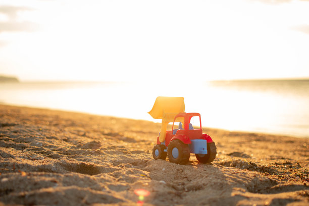 在沙滩上挖掘玩具车。图片下载
