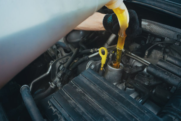 维修人员在车库里向发动机注入机油，关闭图片下载