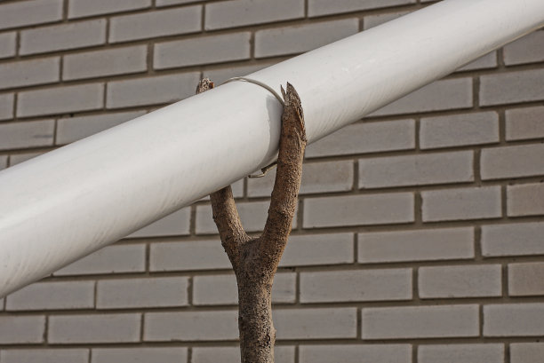 灰色木挡上有一条白色的塑料排水管图片下载