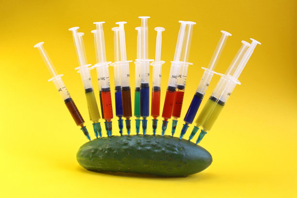 许多带有明亮药物的注射器插在黄瓜上。图片下载