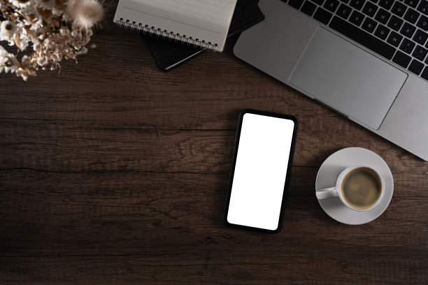 木制办公桌上摆放着智能手机、笔记本电脑、咖啡杯和记事本。为你的文本复制空间。图片下载