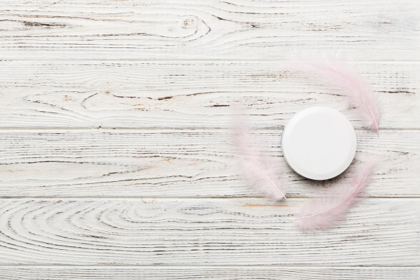 一套皮肤护理血清在粉红色粉彩背景与鸵鸟羽毛。Spa化妆品，奶油罐，品牌模型，顶部视图与复制空间图片下载