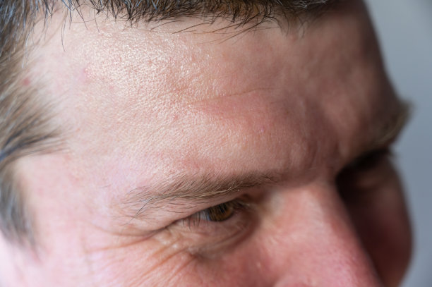 男性面部的上部。一个眼睛附近有皱纹的成熟男人。棕色的短头发。特写镜头。有选择性的重点。图片下载