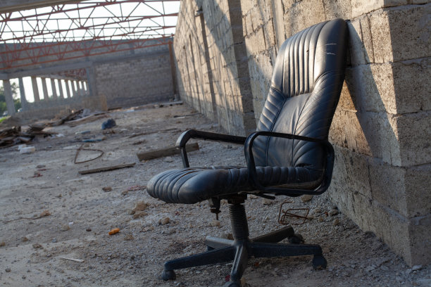 空的黑色椅子，背景是肮脏的垃圾砖墙图片下载