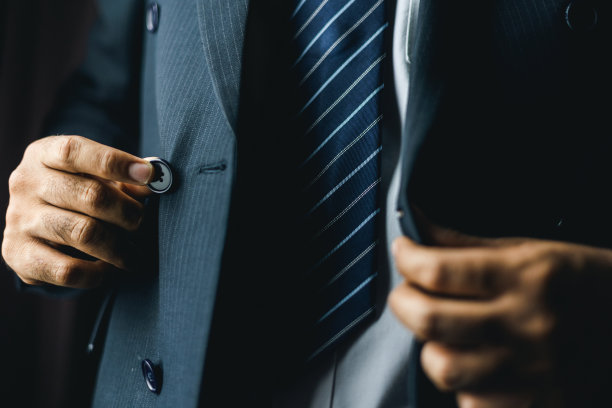 清晨，自信的商人在酒店房间靠窗处系扣子或调整经典的蓝色西装。一个帅哥在婚礼上穿了一套漂亮的西装。图片下载