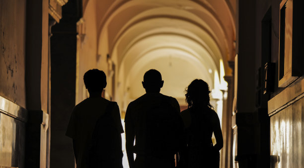 建筑走廊上三个人的剪影，光影交错图片下载
