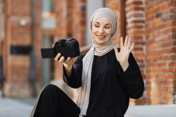 年轻的穆斯林妇女使用摄像机为她的工作录制视频。图片下载