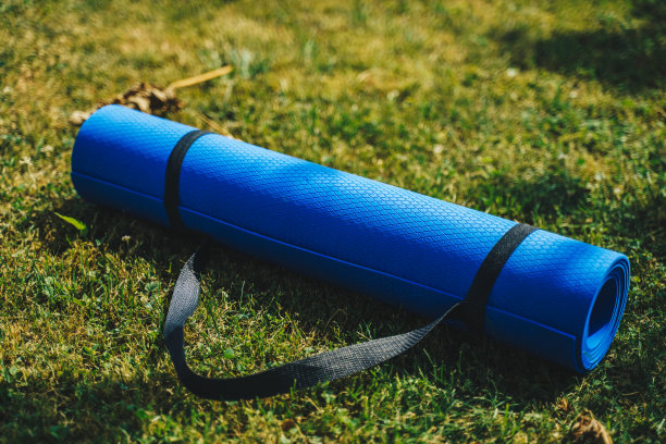蓝色的运动垫子在新鲜的绿色草地户外，近距离库存照片图片下载