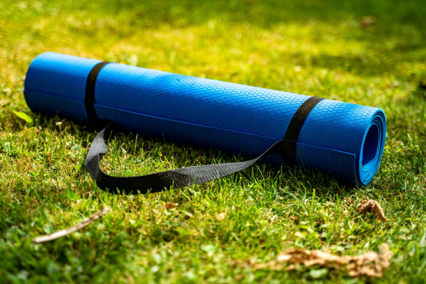 蓝色的运动垫子在新鲜的绿色草地户外，近距离库存照片图片下载
