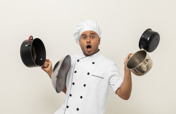 年轻搞笑的亚洲男厨师端着许多汤锅和各种厨房用具准备做饭。印度男子职业厨师餐厅和酒店。图片下载