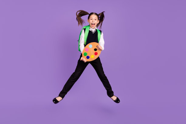 照片开朗的艺术家女生跳hold油漆托盘穿双肩包统一孤立的紫色背景图片下载