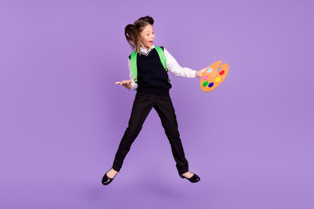 高兴兴奋的画家女生抱着托盘张开嘴穿包统一孤立的紫色背景的照片图片下载